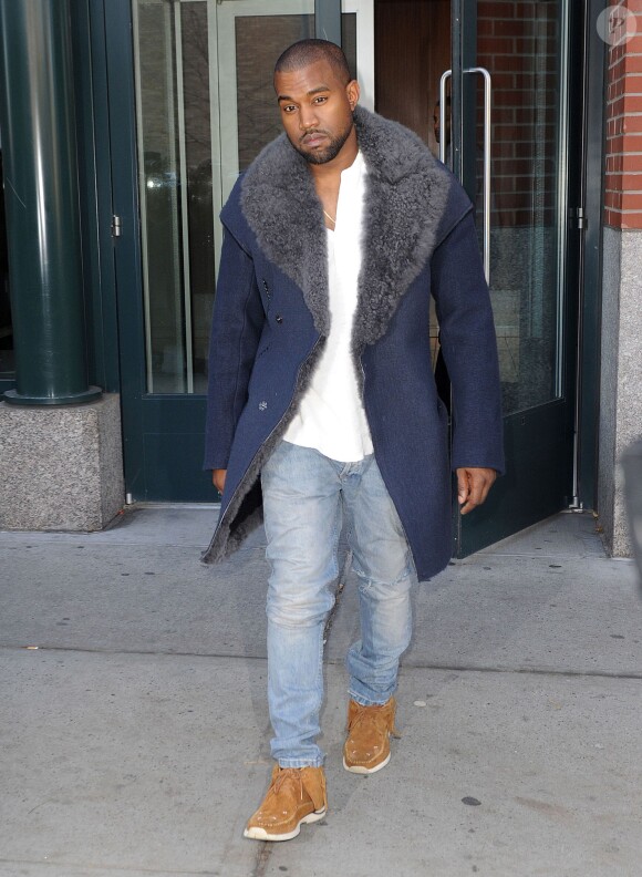 Kanye West sort de son appartement à SoHo, habillé d'un manteau Lanvin (collection automne-hiver 2012), un top blanc RRL (par Ralph Lauren), un jean clair et des chaussures Visvim. New York, le 20 novembre 2013.