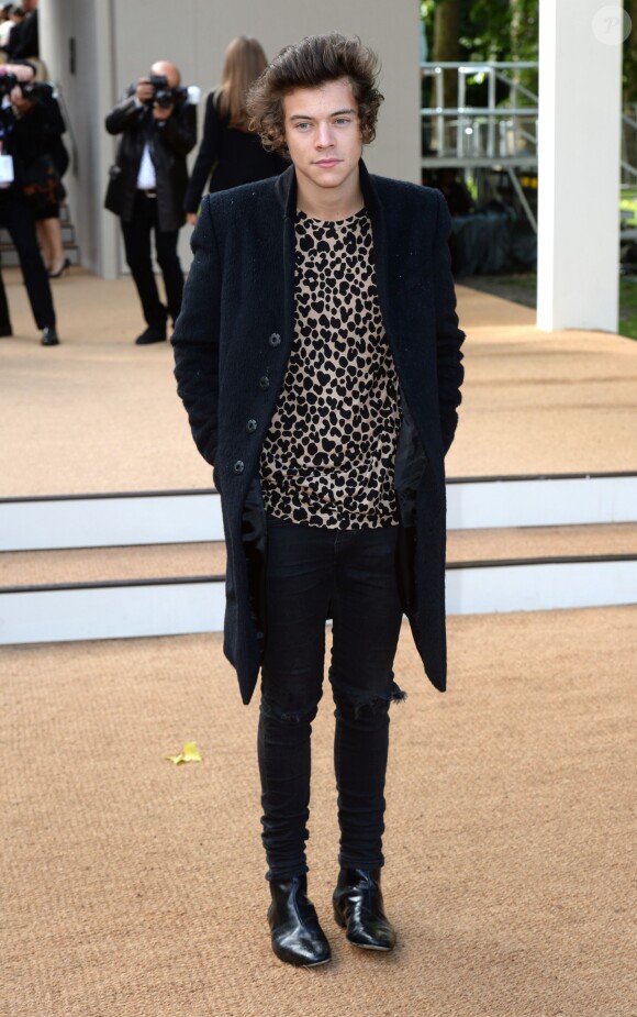Harry Styles, en manteau et t-shirt Burberry Prorsum (collection automne-hiver 2013) lors du défilé printemps-été 2014 de la marque anglaise. Londres, le 16 septembre 2013.