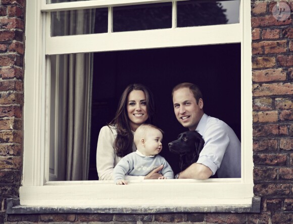 Kate Middleton et le prince William avec le prince George et Lupo, le chien de la famille, à la fenêtre de leur domicile de Kensington Palace, l'appartement 1A, en mars 2014. Une photo révélée le 30 mars 2014, jour de la Fête des Mères en Grande-Bretagne.
