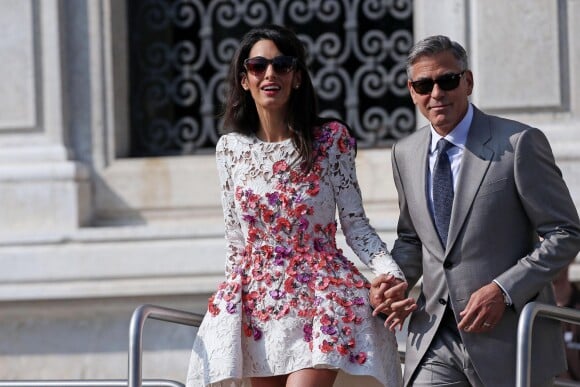 George Clooney et Amal Alamuddin (en Giambattista Valli), portant leurs alliances, apparaissent pour la première fois après leur mariage, le 28 septembre 2014, quittant l'Aman Grande Canal Venice après leur nuit de noces pour rallier le Cipriani pour un brunch avec leurs proches.