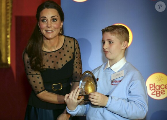 Kate Middleton, enceinte de quatre mois, récompense le jeune Bailey Dunne à Kensington Palace, à Londres, le 19 novembre 2014. A deux pas de son domicile, la duchesse de Cambridge, en haut Hobbs et jupe Jenny Packham, remettait ce soir-là les prix de l'association Place2Be dont elle est la marraine depuis 2013.