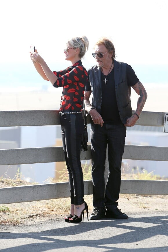 Johnny Hallyday et sa femme Laeticia, en chemisette tout en transparence, sont allés se promener en moto aux alentours de Los Angeles. Le couple a déjeuné en amoureux chez "Blue Plate" à Santa Monica, avant de se faire prendre en photo devant la plage de Santa Monica, le 27 septembre 2014.