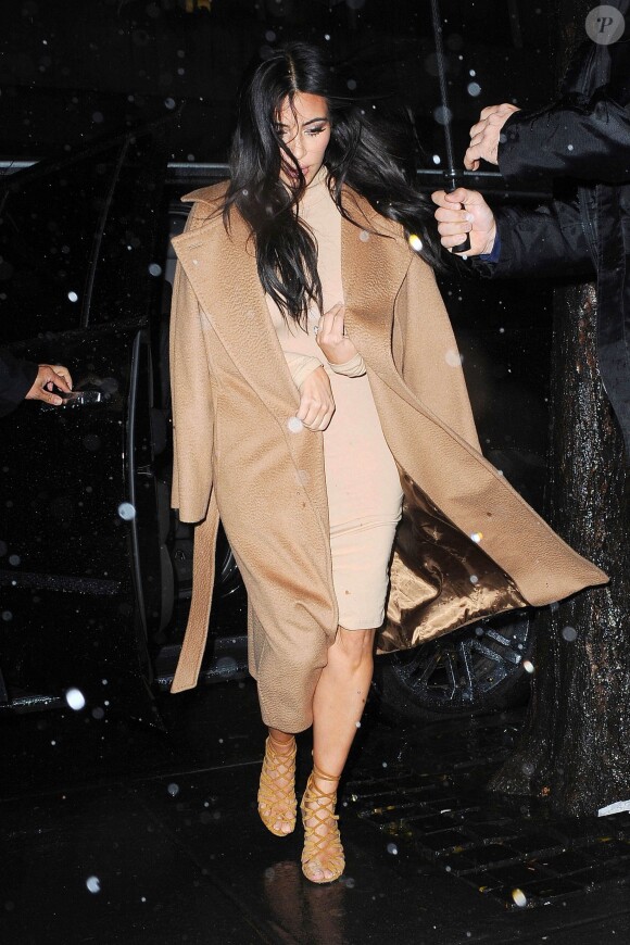 Kim Kardashian sous la pluie et tout de marron vêtue à Manhattan, New York, porte un manteau Max Mara (modèle Manuela), une robe American Apparel et des sandales Hermès. Le 9 décembre 2014.