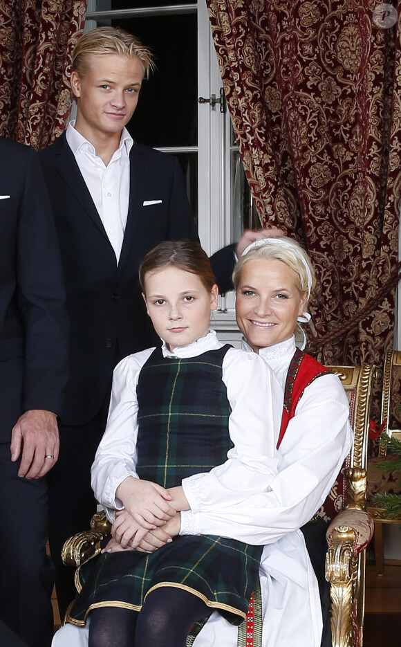 Ingrid Alexandra sur les genoux de la princesse Mette-Marit. Les membres de la famille royale de Norvège - le roi Harald, la reine Sonja, le prince Haakon, la princesse Mette-Marit, la princesse Ingrid Alexandra (10 ans), le prince Sverre Magnus (9 ans) et Marius Borg (17 ans) - ont pris la pose au palais le 17 décembre 2014 pour les fêtes de Noël.