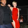Miley Cyrus dans une belle robe rouge s'accroche à son garde du corps alors qu'elle quitte le bar à cocktails Hooray Henry's à Los Angeles avec son petit ami Patrick Schwarzenegger, le 7 février 2015.