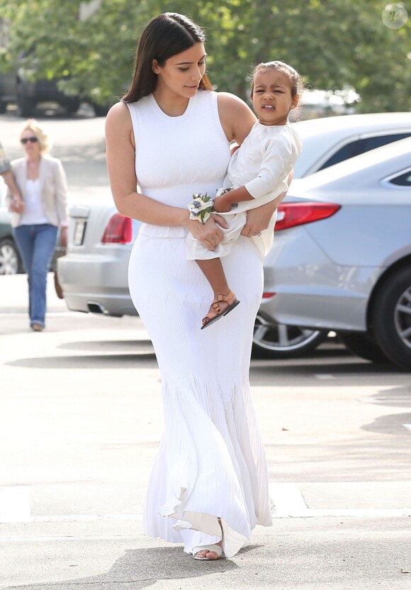 Kim Kardashian, tout de blanc vêtue avec un top et une jupe Alaïa, quitte une église avec sa fille North. Woodland Hills, le 5 avril 2015.
