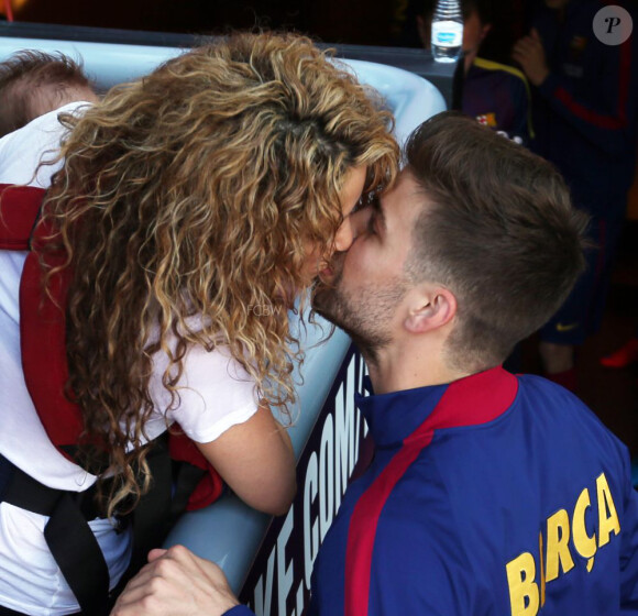 Shakira embrasse Gerard Piqué au Camp Nou le 18 avril 2015 lors du match FC Barcelone - FC Valence. Aidée par sa belle-mère Montserrat Bernabeu, elle était venue avec ses enfants Milan (2 ans) et Sasha (3 mois) encourager son chéri.