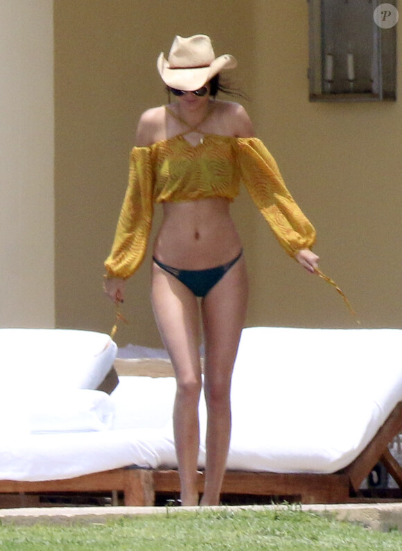 Kendall Jenner se dore la pilule à Punta Mita au Mexique, habillée d'un bikini vert algue Mikoh. La star de télé-réalité/mannequin de 19 ans porte également un top jaune, des lunettes Saint Laurent et un chapeau. Le 13 août 2015.