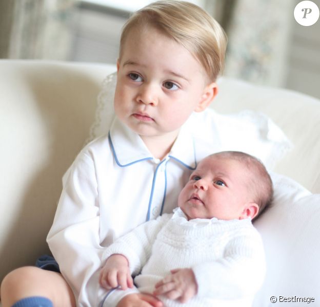 Le prince George de Cambridge avec sa petite soeur la princesse Charlotte dans les bras deux semaines après sa naissance, en mai 2015, photographiés dans leur maison de campagne d'Anmer Hall par leur mère la duchesse Catherine de Cambridge.