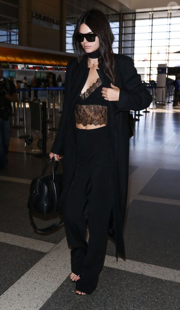 Kendall Jenner à l'aéroport de Los Angeles, porte un manteau Ann Demeulemeester, un top en dentelle Sharon Wauchob et un pantalon Sally LaPointe. Des lunettes de soleil Céline et un sac Givenchy (modèle Lucrezia) complètent sa tenue. Le 28 septembre 2015.