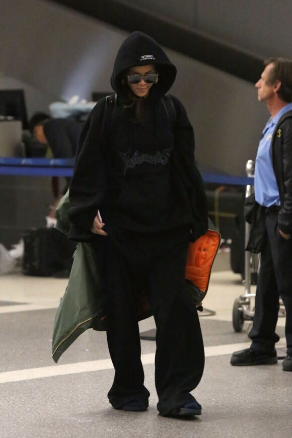 Rihanna à l'aéroport LAX, porte un pull, un jogging et un bomber oversize Vetements, un sac à dos Givenchy et des sandales Puma. Le 6 octobre 2015.