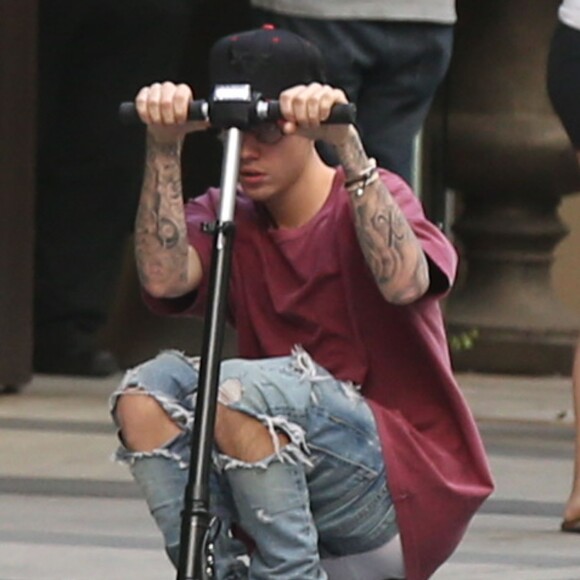 Justin Bieber fait de la trottinette devant son hôtel à Hollywood. Il porte des lunettes de vue rondes le 24 novembre 2015