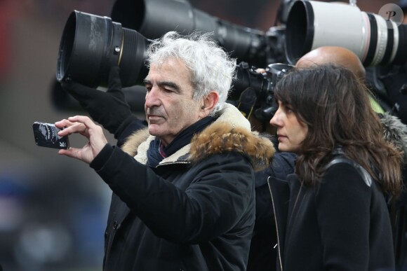 Raymond Domenech et sa compagne Estelle Denis lors du match de Ligue 1 PSG-Lyon lors de la 18e journée au Parc des Princes à Paris, le 13 décembre 2015.