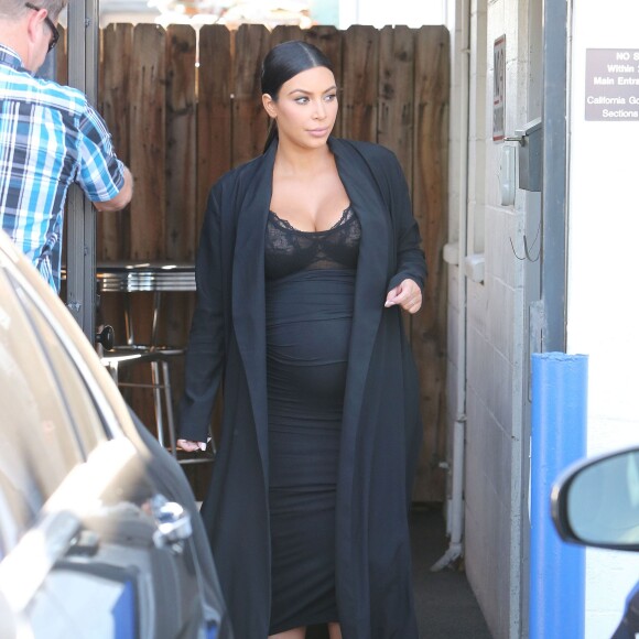 Kim Kardashian, enceinte, est toujours coiffée et maquillée à la perfection quand elle sort à Los Angeles le 23 octobre 2015. Kim, qui a célébré ses 35 ans le 21 octobre dernier, sort habillée d'un long manteau noir et d'une robe près du corps qui ne laisse aucun doute sur sa maternité.