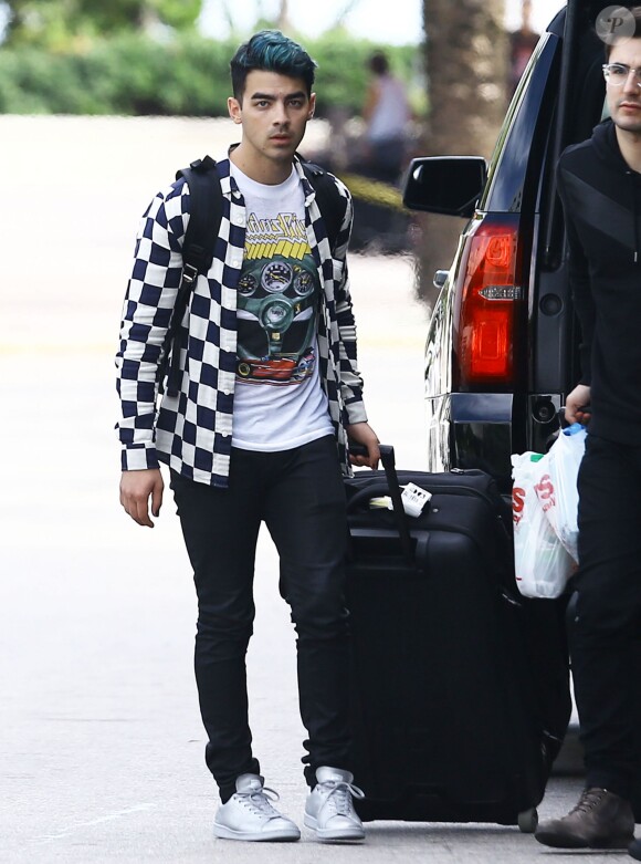 Exclusif - Le chanteur Joe Jonas arrive à l'aéroport de Miami en compagnie d'un groupe d'amis le 18 décembre 2015.