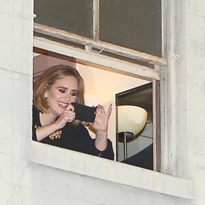 Adele dit bonjour à ses fans depuis sa fenêtre avant son concert au Wiltern Theatre à Los Angeles, le 12 février 2016