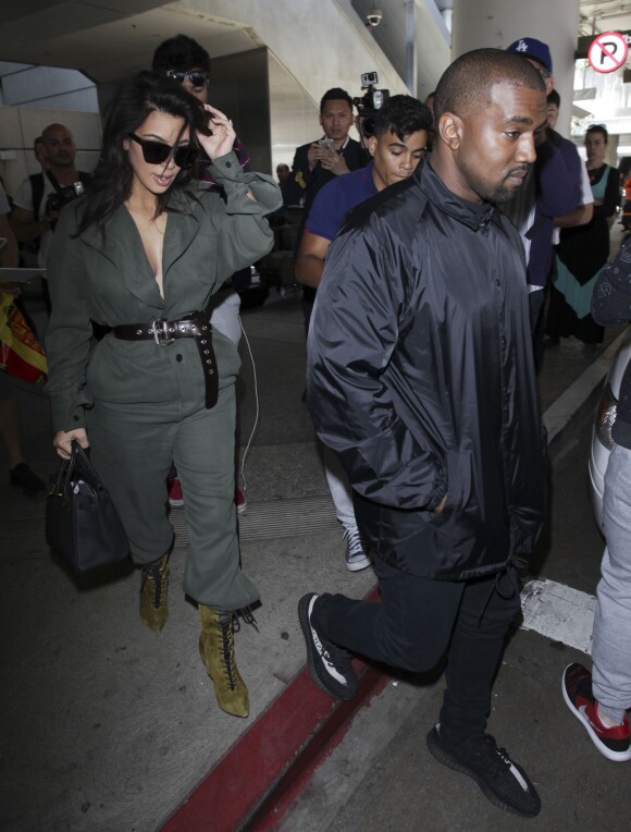 Kim Kardashian portant un décolleté très généreux, et son mari Kanye West arrivent à l'aéroport de Los Angeles (LAX), le 24 mai 2016.