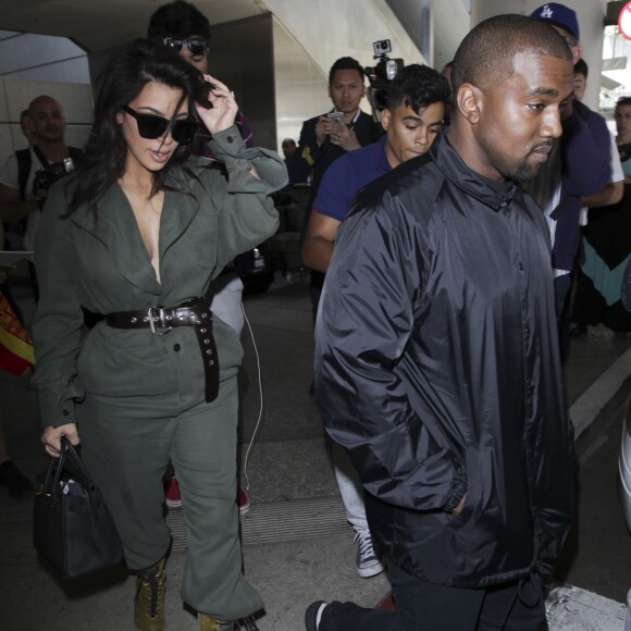 Kim Kardashian portant un décolleté très généreux, et son mari Kanye West arrivent à l'aéroport de Los Angeles (LAX), le 24 mai 2016.