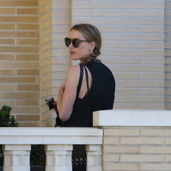 Exclusif - Amber Heard avec son petit chien dans les bras et accompagnée d'un garde du corps, sort de la boutique "Barneys New York" à Beverly Hills. Los Angeles, le 12 juillet 2016.