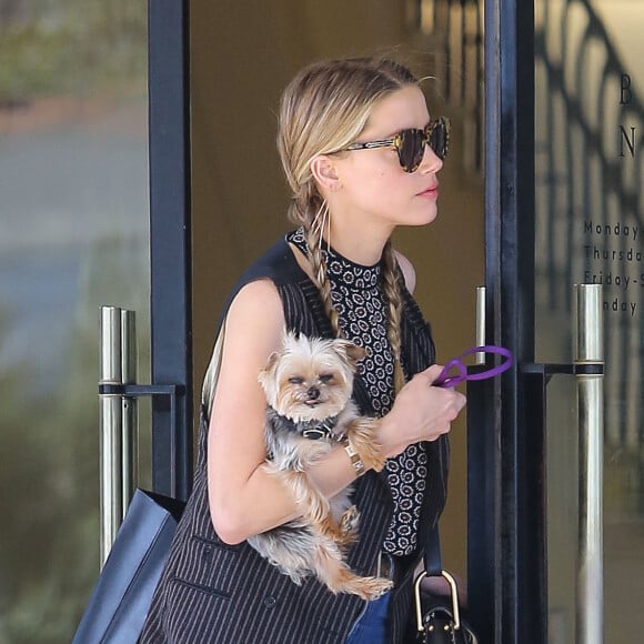 Exclusif - Amber Heard avec son petit chien dans les bras et accompagnée d'un garde du corps, sort de la boutique "Barneys New York" à Beverly Hills. Los Angeles, le 12 juillet 2016.