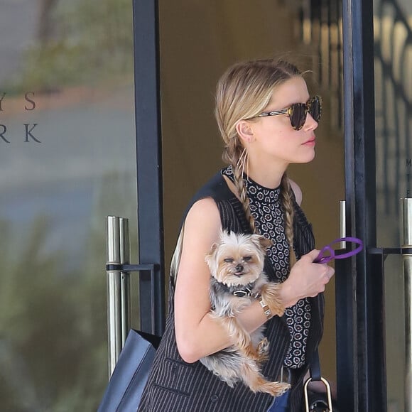 Exclusif - Amber Heard avec son petit chien dans les bras et accompagnée d'un garde du corps, sort de la boutique "Barneys New York" à Beverly Hills. Los Angeles, le 12 juillet 2016.