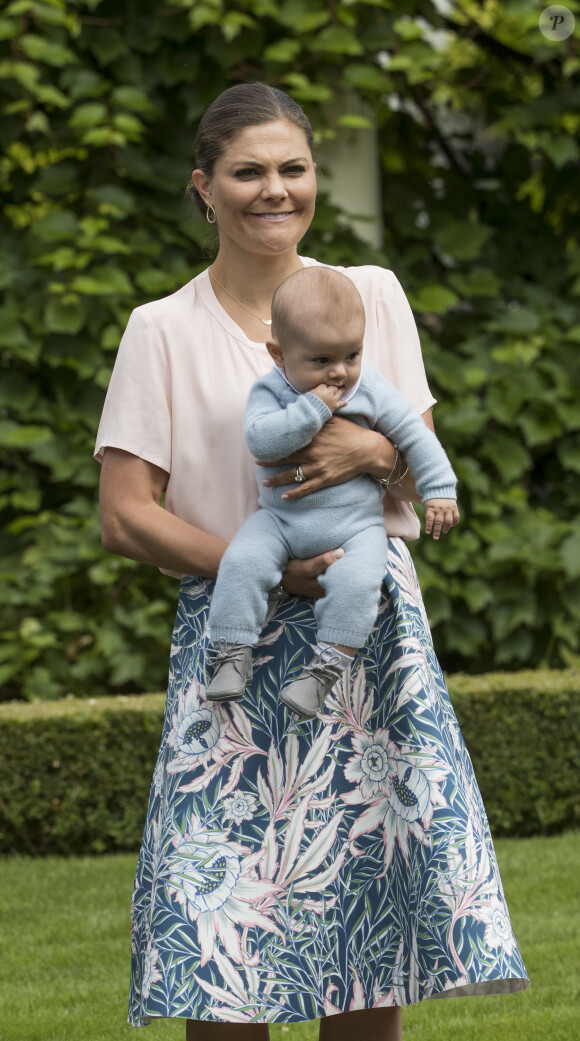 La princesse Victoria de Suède, ici avec son fils le prince Oscar dans les bras le 15 juillet 2016, a été désignée marraine de son neveu le prince Alexander, baptisé le 9 septembre 2016.