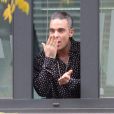 Robbie Williams salue ses fans depuis une fenêtre de la Radio DJ à Milan, le 11 novembre 2016.