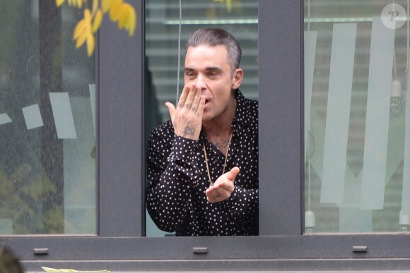 Robbie Williams salue ses fans depuis une fenêtre de la Radio DJ à Milan, le 11 novembre 2016.