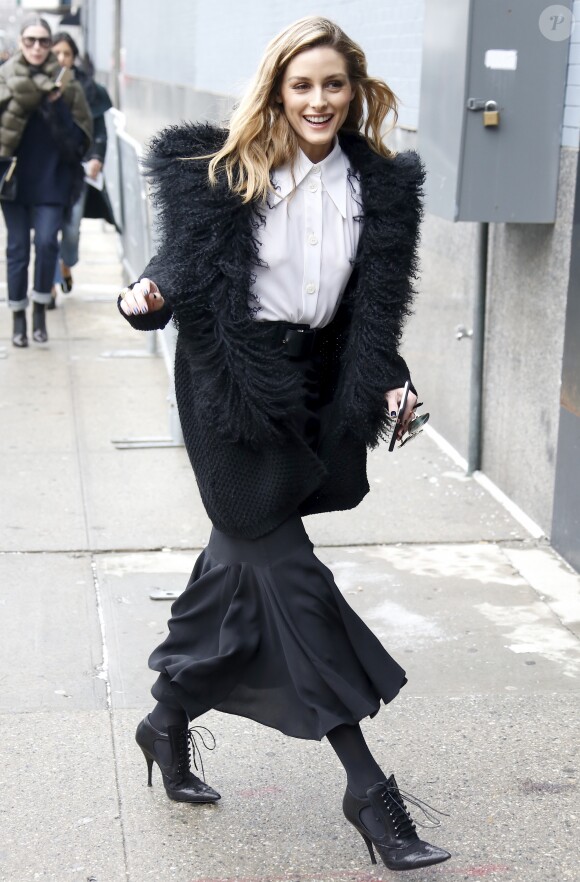 Olivia Palermo arrive au défilé Michael Kors Collection, habillée d'un manteau noir, d'une chemise, d'une jupe et d'une ceinture Michael Kors Collection (collection printemps 2017) et de chaussures Givenchy. New York, le 15 février 2017.