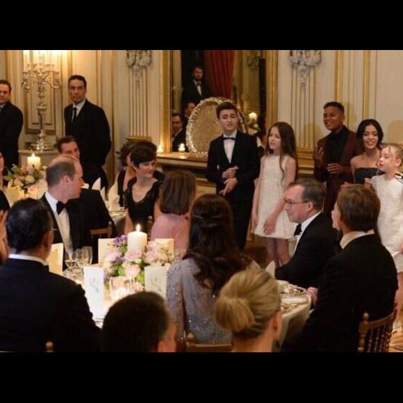 Le prince William et Kate Middleton observant les Kids United en train de chanter leur reprise du tube Happy lors du dîner de gala organisé le 17 mars 2017 à la résidence de l'ambassadeur de Grande-Bretagne à Paris, au premier soir de la visite officielle du duc et de la duchesse de Cambridge. Happy, l'une des chansons au son desquelles le prince William se déchaînait quelques jours plus tôt à Verbier...