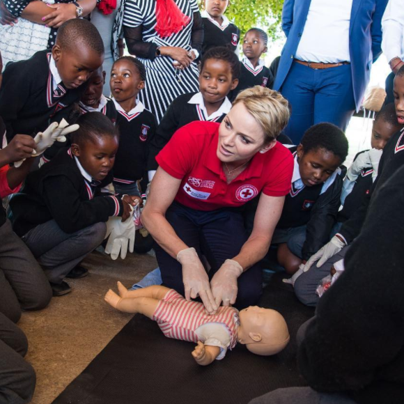 La princesse Charlene de Monaco montrant les gestes de premiers secours et de réanimation cardio-pulmonaire lors d'une visite ena vril 2017 à l'école primaire Gugulesizwe à Benoni en Afrique du Sud, où elle avait lancé en 2012 sa fondation. Photo Instagram officiel HSH Princess Charlene.