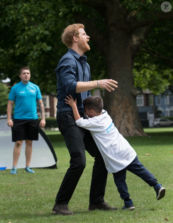 Le prince Harry joue avec des enfants lors de sa visite du centre de loisirs Newham Council's à Central Park à Londres, le 28 juillet 2017.