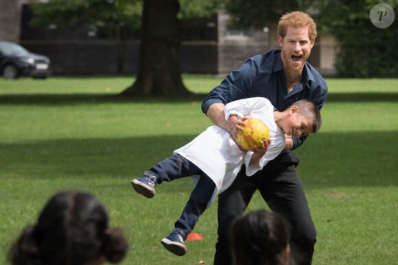 Le prince Harry joue avec des enfants lors de sa visite du centre de loisirs Newham Council's à Central Park à Londres, le 28 juillet 2017.