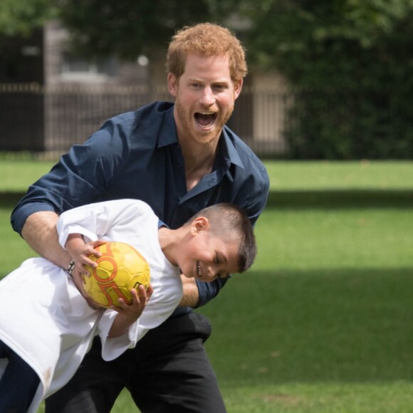 Le prince Harry joue avec des enfants lors de sa visite du centre de loisirs Newham Council's à Central Park à Londres, le 28 juillet 2017.