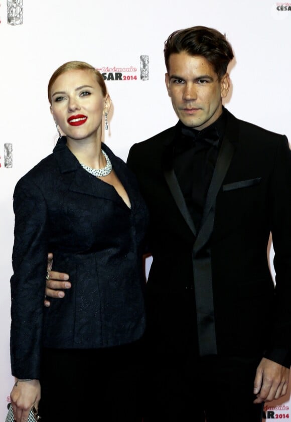 Scarlett Johansson (César d'honneur) (habillée avec une veste « Bar » en dentelle bleu marine, pantalon en crêpe de soie bleu marine et une pochette Dior) et Romain Dauriac -39e cérémonie des César au théâtre du Châtelet à Paris Le 28 février 2014