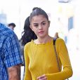 Selena Gomez se promène dans les rues de New York. L'actrice porte un haut jaune moutarde sans soutien-gorge, un pantalon noir, des escarpins de la même couleur et un sac Louis Vuitton " Twist MM", le 27 septembre 2017.