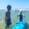 Bixente, le fils de Natasha St-Pier, s'essaye au surf à la plage, sous le regard attendri de son père Grégory Quillacq.
