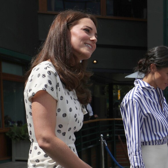 La duchesse Catherine de Cambridge (Kate Middleton) et la duchesse Meghan de Sussex (Meghan Markle) saluent le staff qui officiera lors de la finale dames, à Wimbledon le 14 juillet 2018, quelques dizaines de minutes avant le début de la finale opposant Serena Williams et Angelique Kerber.