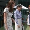 La duchesse Catherine de Cambridge (Kate Middleton) et la duchesse Meghan de Sussex (Meghan Markle) saluent le staff qui officiera lors de la finale dames, à Wimbledon le 14 juillet 2018, quelques dizaines de minutes avant le début de la finale opposant Serena Williams et Angelique Kerber.