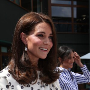 La duchesse Catherine de Cambridge (Kate Middleton) et la duchesse Meghan de Sussex (Meghan Markle) saluent le staff qui officiera lors de la finale dames, à Wimbledon le 14 juillet 2018, quelques dizaines de minutes avant le début de la finale opposant Serena Williams et Angelique Kerber.