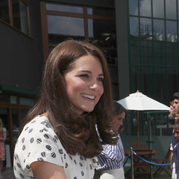 La duchesse Catherine de Cambridge (Kate Middleton) et la duchesse Meghan de Sussex (Meghan Markle) saluent le staff qui officiera lors de la finale dames, à Wimbledon le 14 juillet 2018, quelques dizaines de minutes avant le début de la finale opposant Serena Williams et Angelique Kerber.