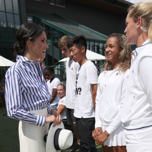 La duchesse Catherine de Cambridge (Kate Middleton) et la duchesse Meghan de Sussex (Meghan Markle) saluent le staff qui officiera lors de la finale dames, à Wimbledon le 14 juillet 2018, quelques dizaines de minutes avant le début de la finale opposant Serena Williams et Angelique Kerber.