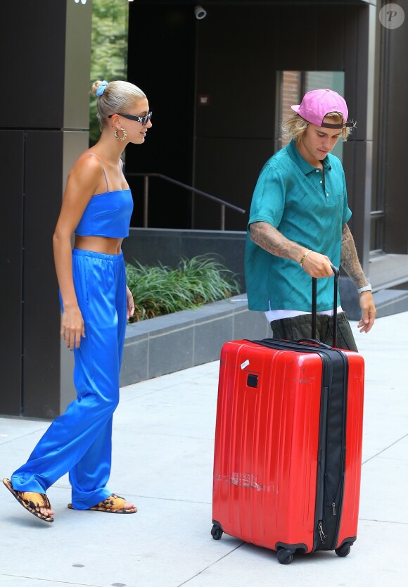 Justin Bieber et sa fiancée Hailey Baldwin sortent d'un immeuble avec des bagages et saluent leurs fans avant de monter dans une voiture à New York, le 13 juillet 2018