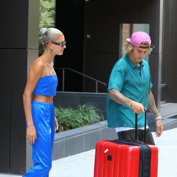 Justin Bieber et sa fiancée Hailey Baldwin sortent d'un immeuble avec des bagages et saluent leurs fans avant de monter dans une voiture à New York, le 13 juillet 2018