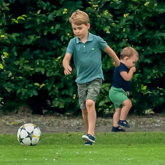 Le prince George de Cambridge et son frère le prince Louis de Cambridge s'amusant pendant un match de polo disputé par le prince William à Wokinghan, le 10 juillet 2019.