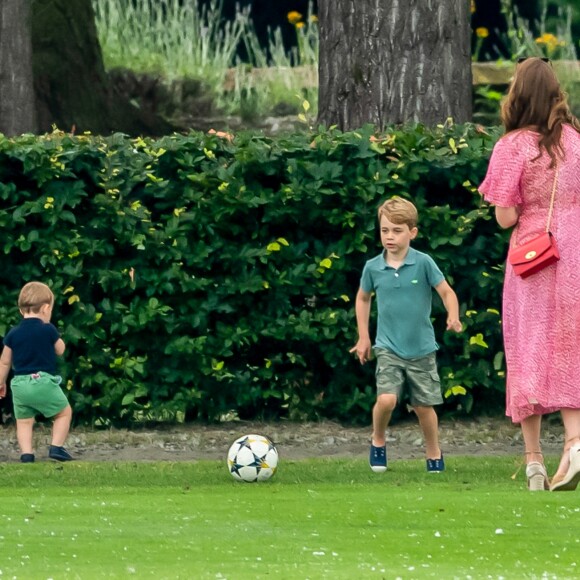 Le prince George de Cambridge et son frère le prince Louis de Cambridge s'amusant sous l'oeil de la duchesse Catherine pendant un match de polo disputé par le prince William à Wokinghan, le 10 juillet 2019.