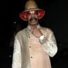 Le père de Drake, Dennis Graham est photographié à la sortie du club Delilah à Los Angeles, le 16 juin 2019. Il porte un long manteau beige scintillant, un chapeau avec une doublure rouge et pour compléter son ensemble de nuit, des lunettes de soleil rouges.