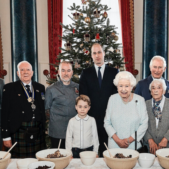 Le prince George de Cambridge prépare, sous le regard bienveillant du prince William, duc de Cambridge, du prince Charles, prince de Galles et de la reine Elisabeth II, des puddings de Noël, dans le cadre du lancement de l'initiative 'Together at Christmas' de la Royal British Legion au Palais de Buckingham, le 21 décembre 2019.