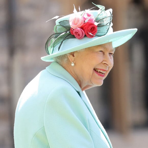 La reine Elisabeth II d'Angleterre remet au capitaine Thomas Moore son titre de chevalier lors d'une cérémonie au château de Windsor, le 17 juillet 2020. Il pose ensuite avec sa famille.