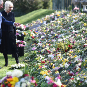 Le prince Charles, prince de Galles et la duchesse de Cornouailles Camila Parker-Bowles passent en revue les hommages au prince Philip dans les jardins de Marlborough House à Londres le 15 avril 2021.